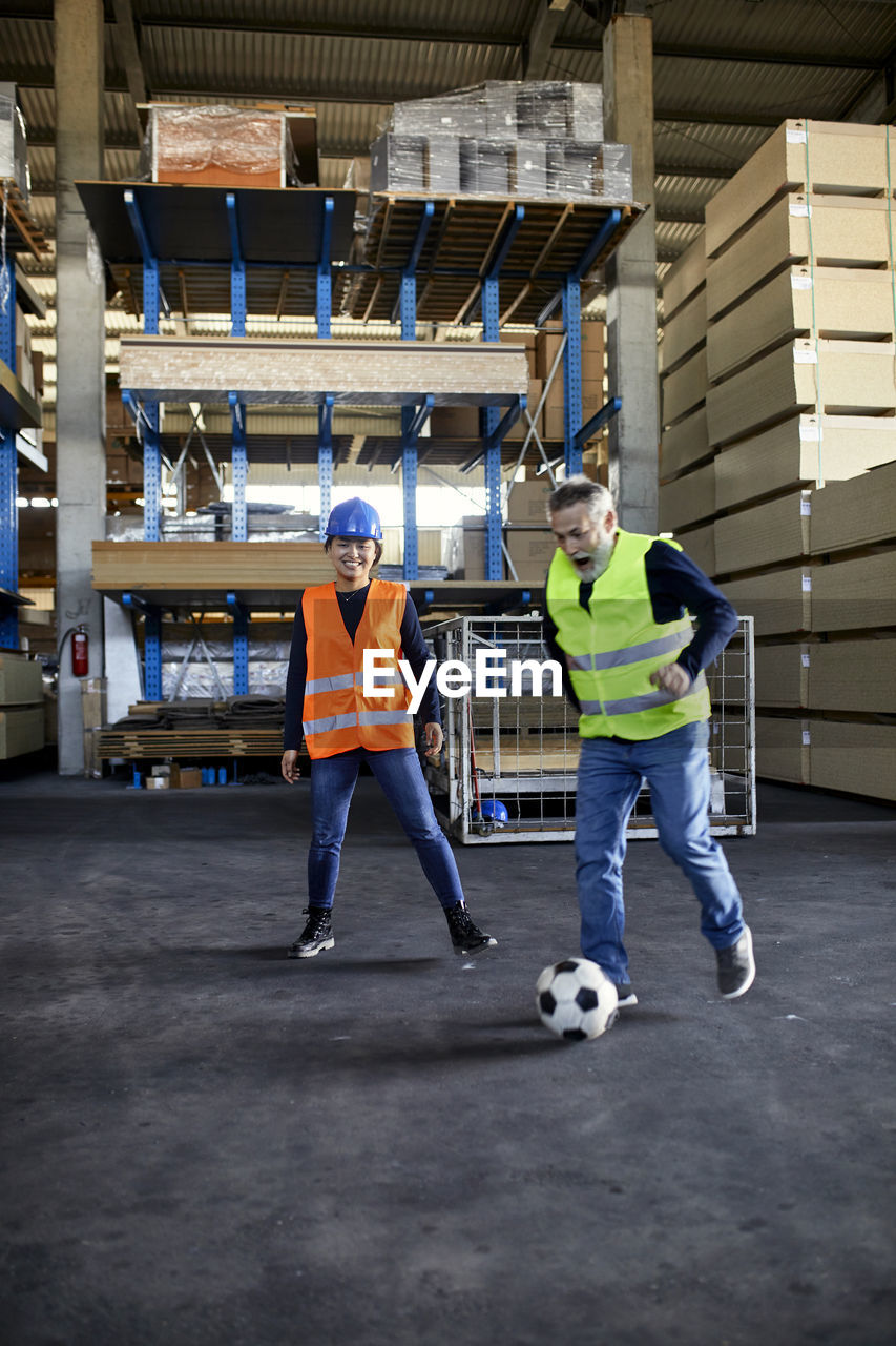 Workers playing football in factory warehouse