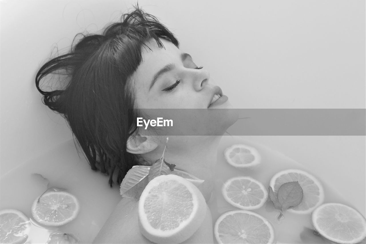 Close-up of woman taking bath with fruits in bathtub