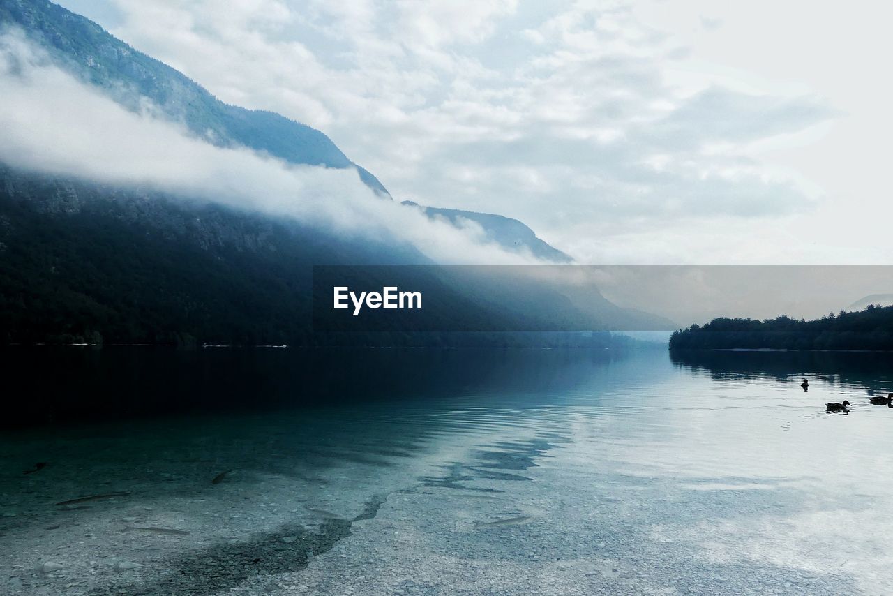 Scenic view of lake by mountains against sky