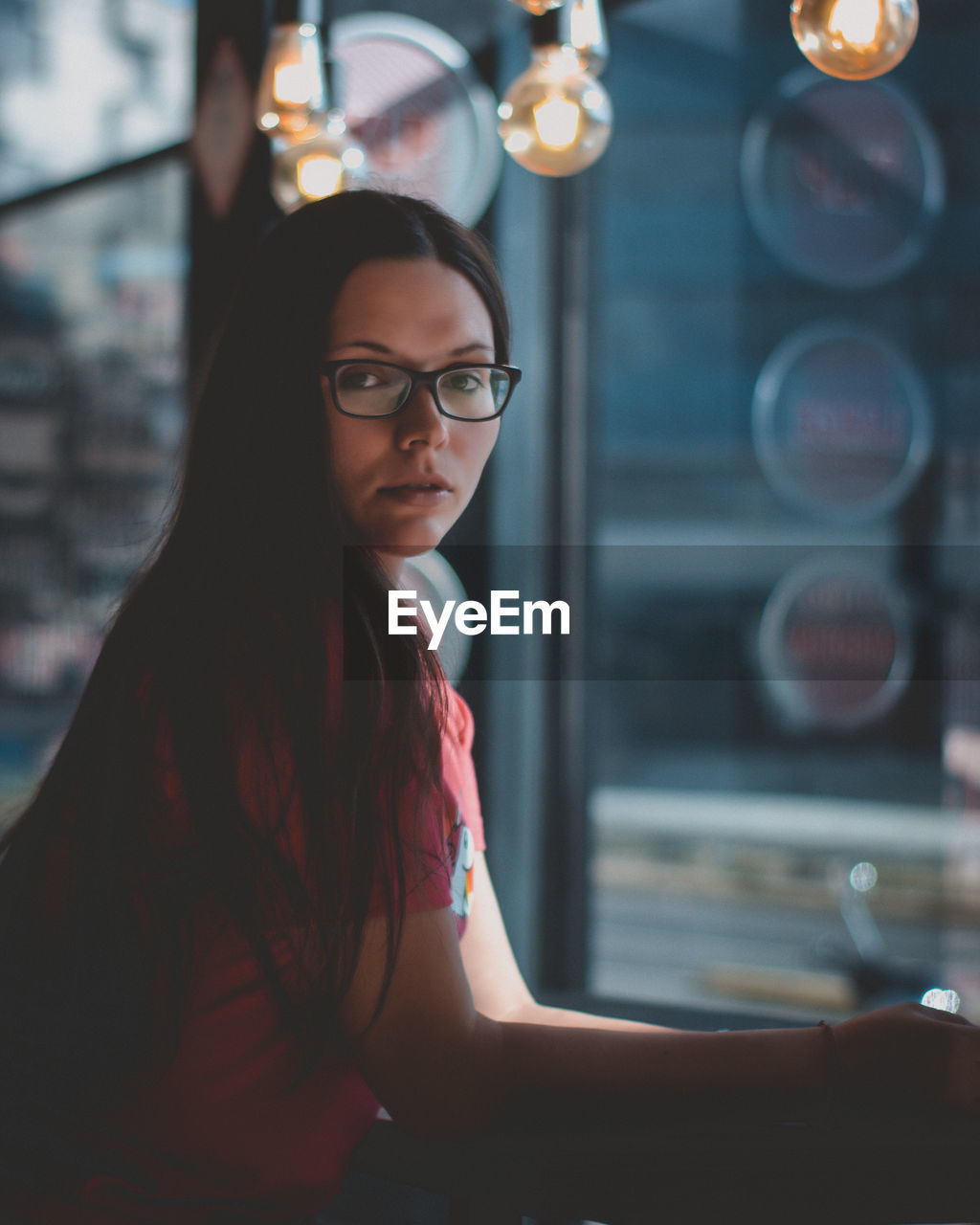 Side view portrait of young woman sitting by window at home