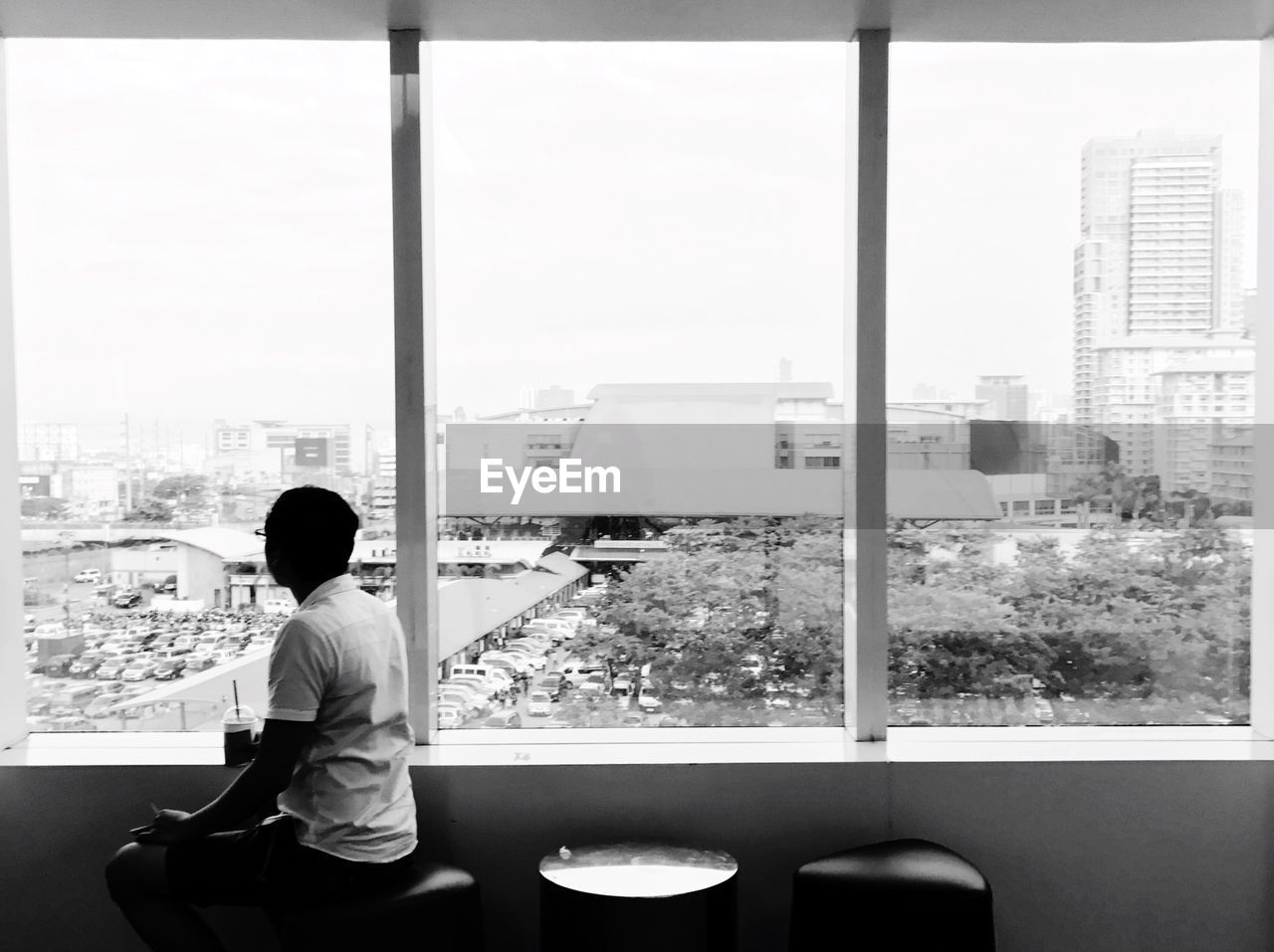 REAR VIEW OF MAN SITTING ON WINDOW