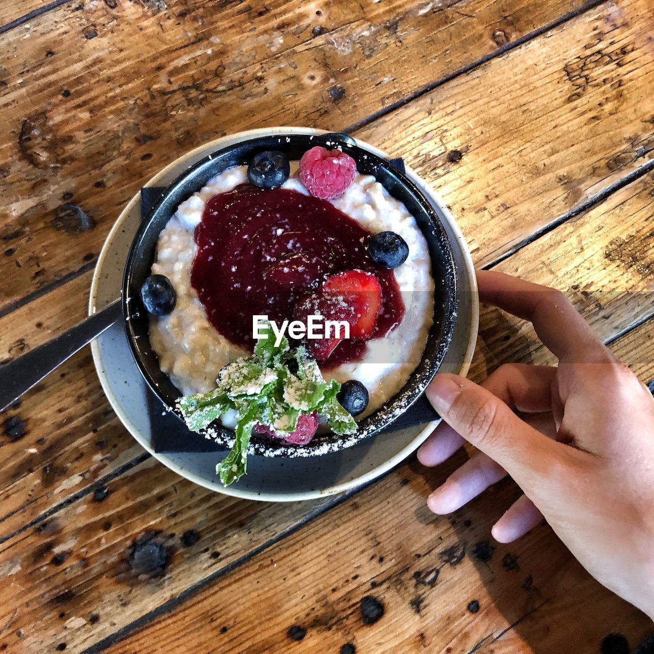 HIGH ANGLE VIEW OF WOMAN HOLDING BOWL OF BREAKFAST