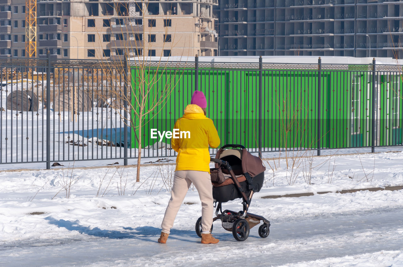 Full length rear view of woman standing in snow