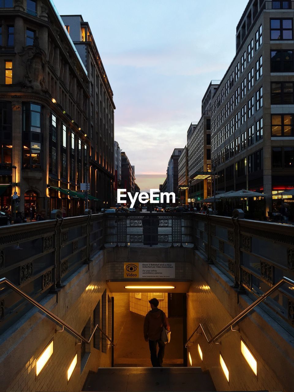 Man moving down subway station amidst buildings against sky