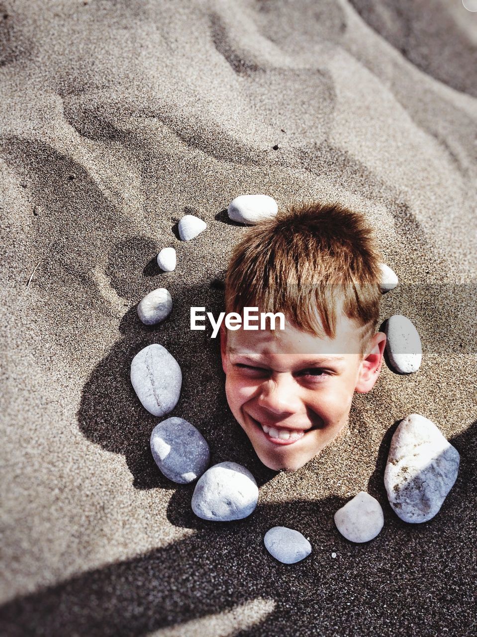 High angle portrait of smiling boy in sand at beach