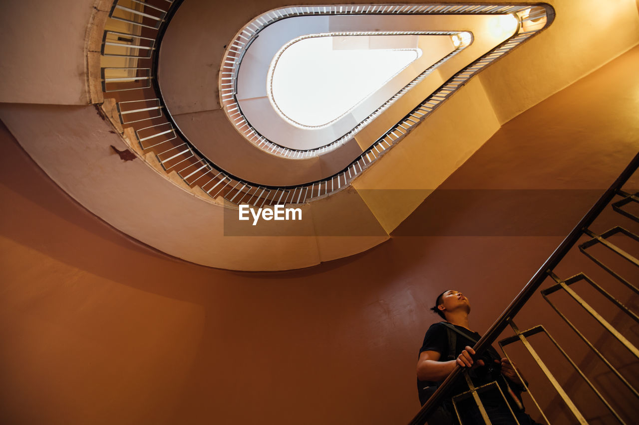 LOW ANGLE VIEW OF WOMAN STANDING ON STAIRCASE