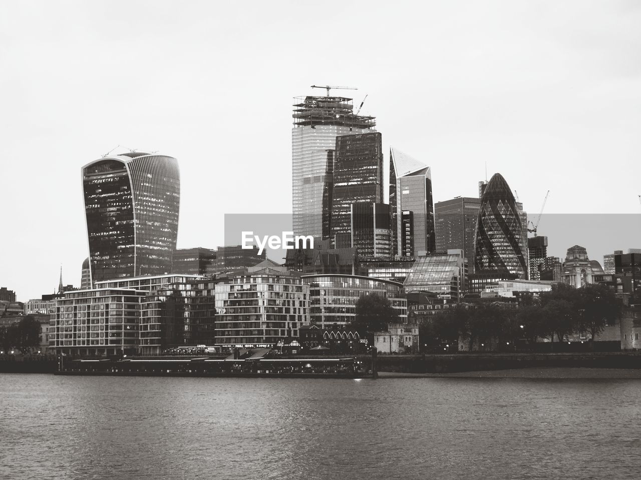 MODERN BUILDINGS BY RIVER AGAINST SKY