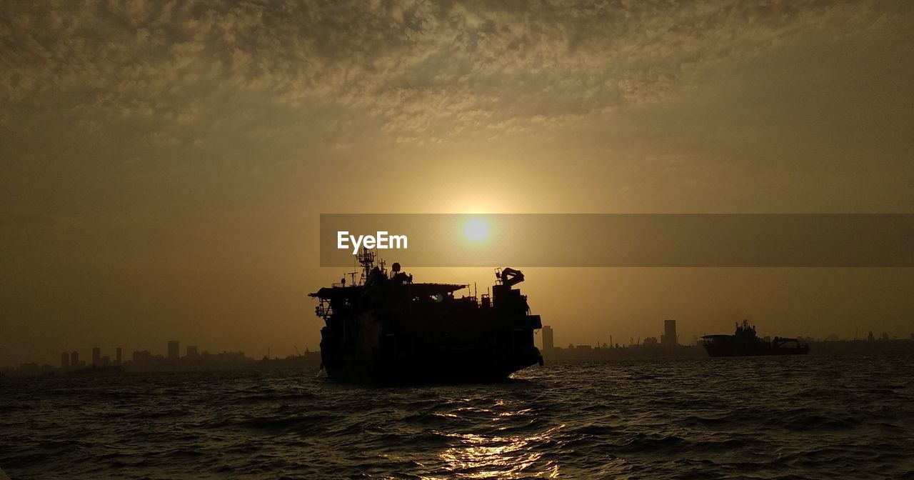 Silhouette ship in sea against sky during sunset