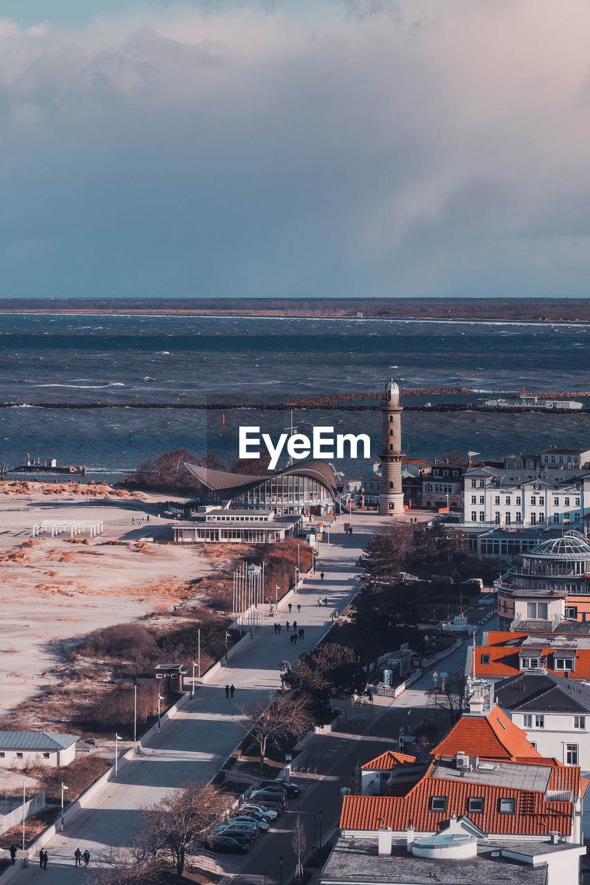 High angle view of buildings by sea against cloudy sky during sunset