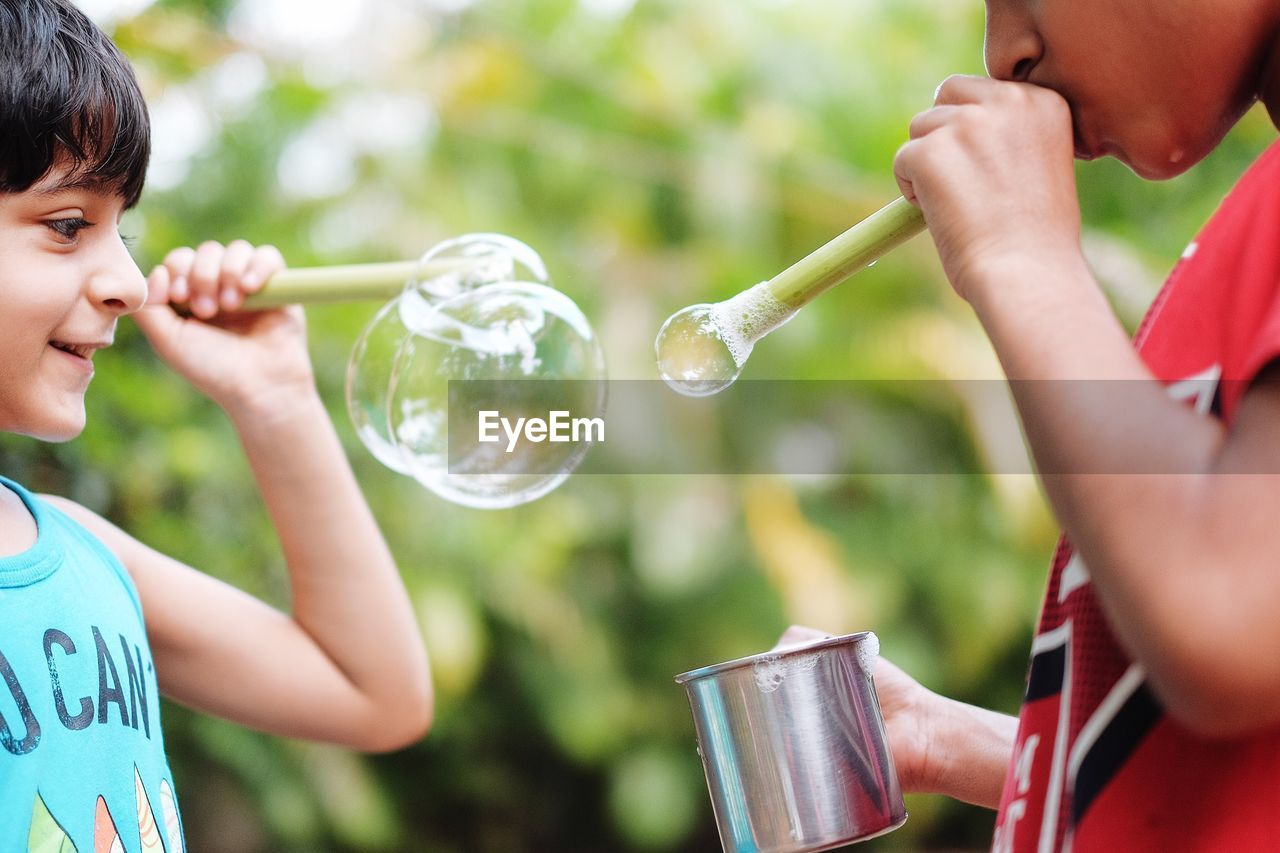 CLOSE-UP OF BOY HOLDING BUBBLES WITH BUBBLE