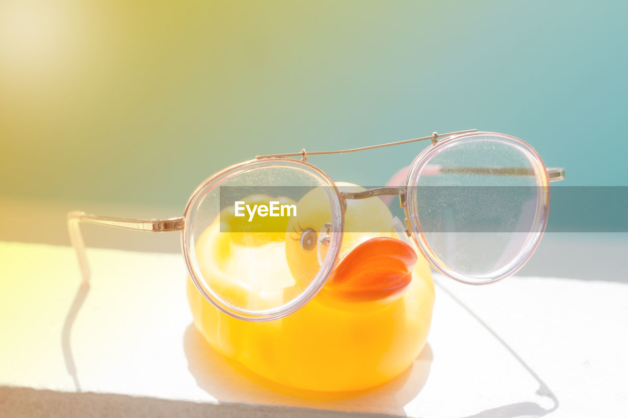 Eyeglasses and rubber duck on wall in sunny day