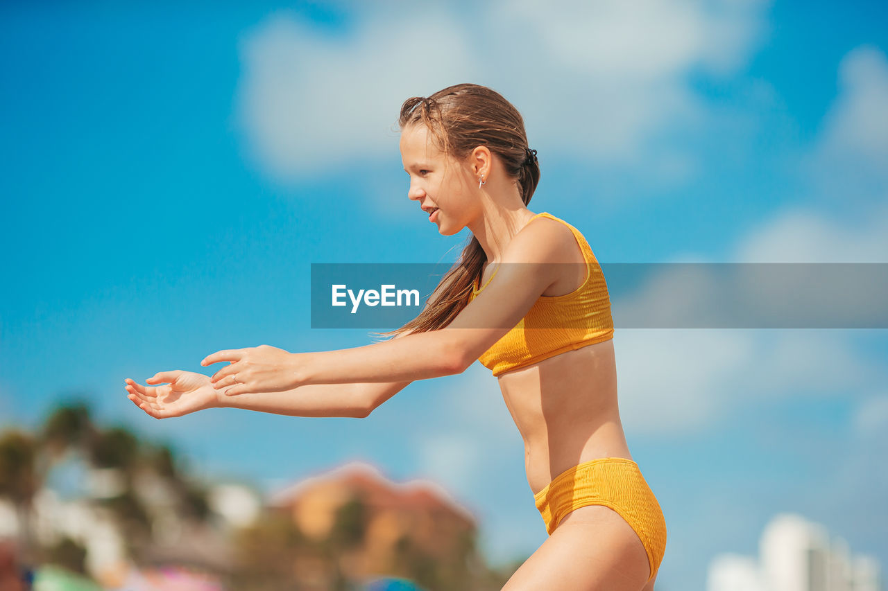 side view of young woman doing yoga against sky