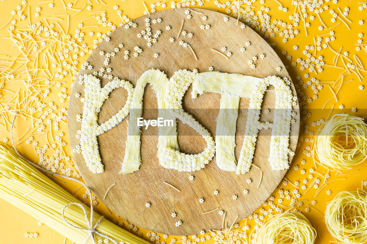 Directly above shot of pasta text made with food on cutting board at table