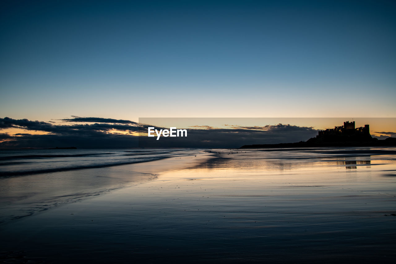 SCENIC VIEW OF BEACH AGAINST SKY AT SUNSET