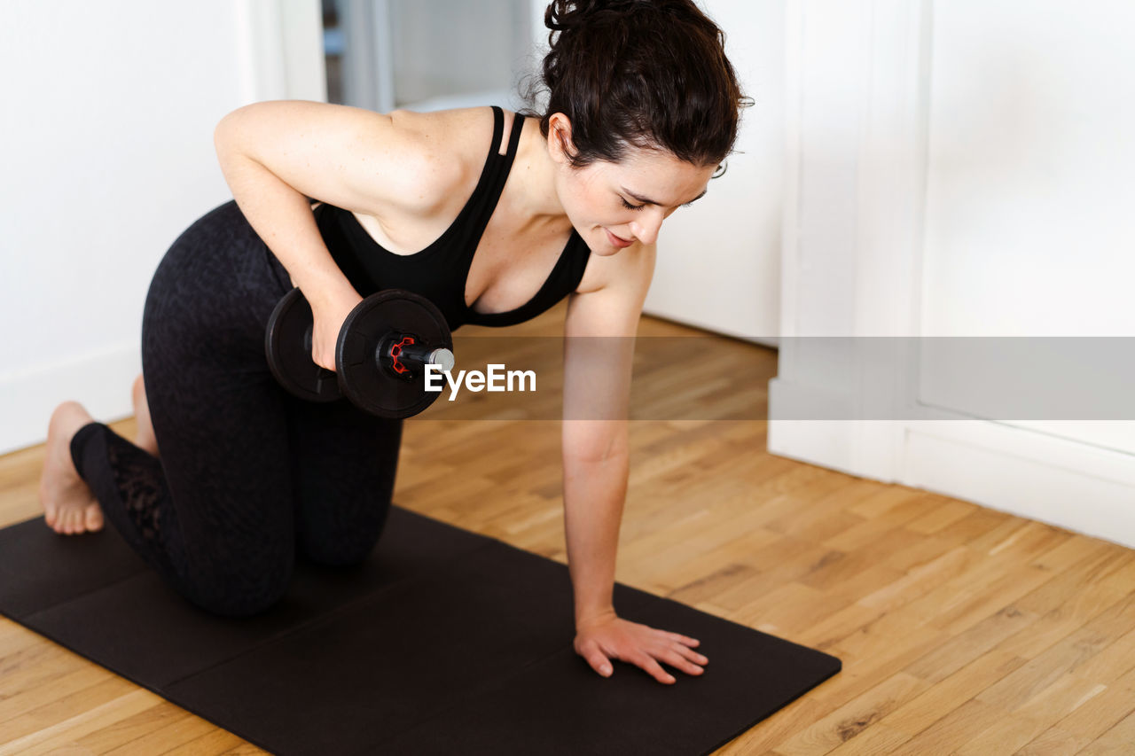 full length of young woman exercising in gym