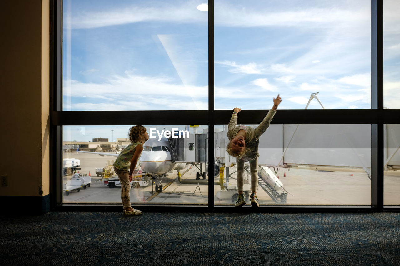 Two girls bored and playing in airport waiting to board plane