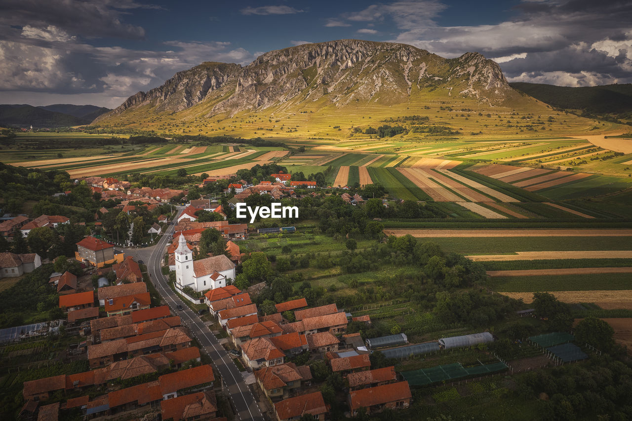 Drone view of a beautiful village with white church and a mountain in the background.