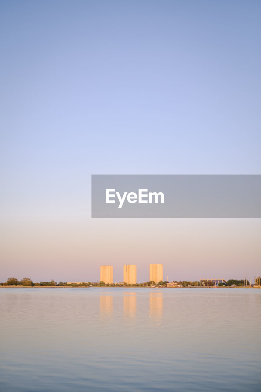Scenic view of buildings behind sea against clear sky