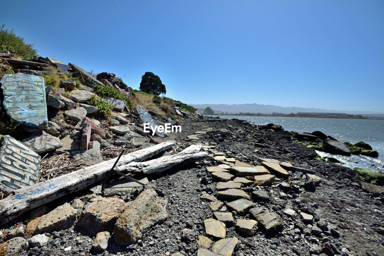 Scenic view of sea by mountain against clear sky