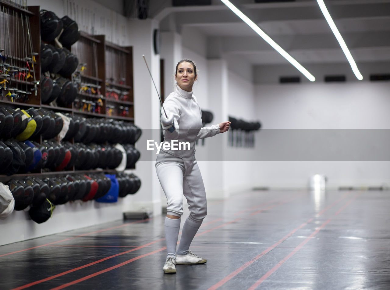 Woman in fencing outfit practicing at gym