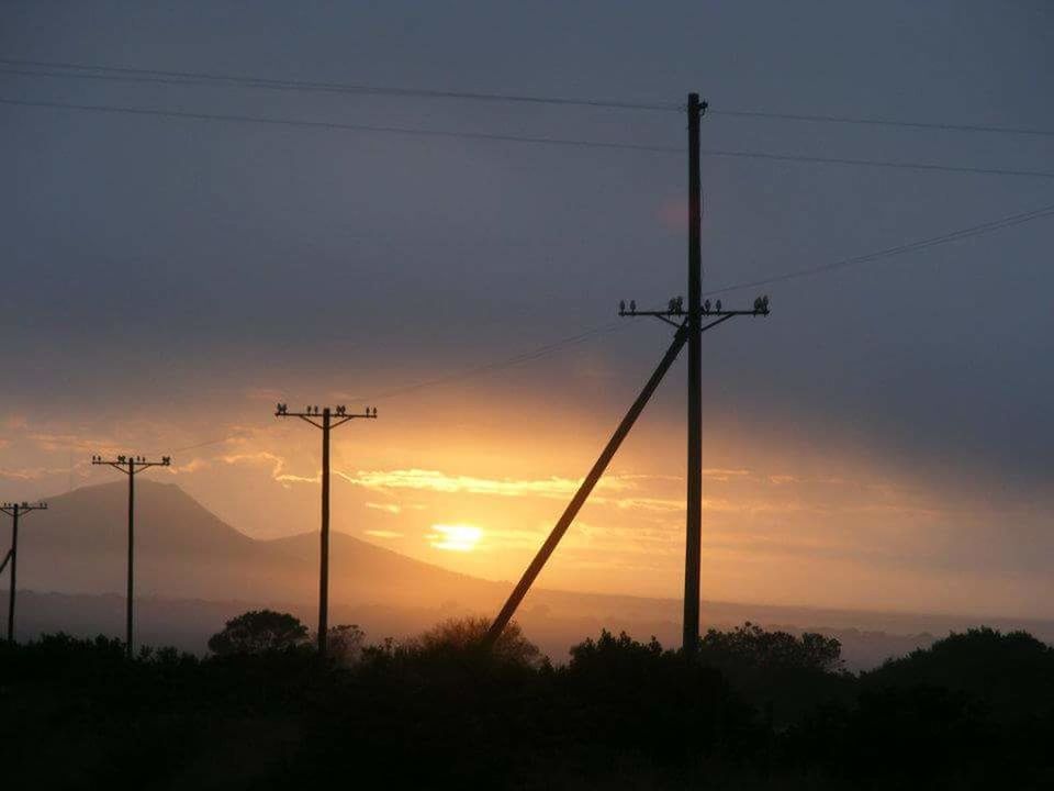 LOW ANGLE VIEW OF ELECTRICITY PYLON AT SUNSET