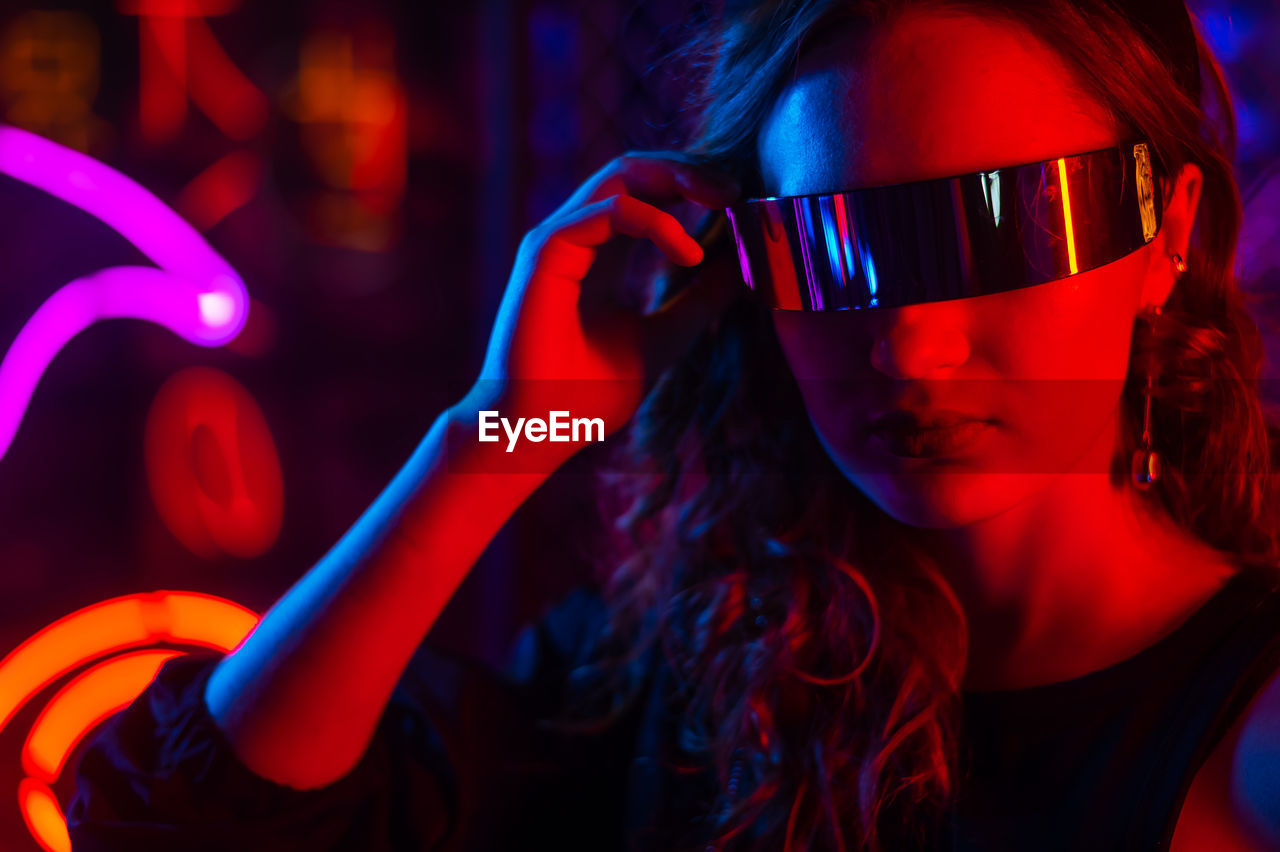 Caucasian woman in sunglasses posing in fog in neon studio