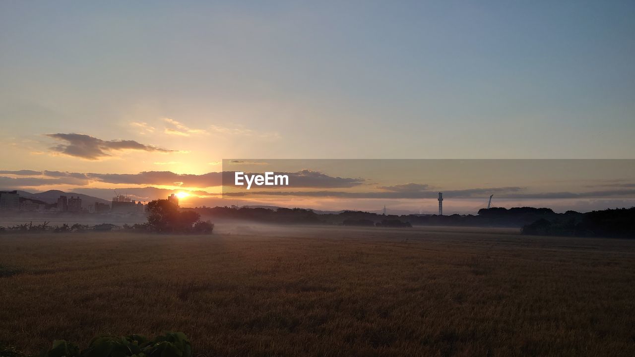 sky, horizon, morning, sunrise, environment, dawn, landscape, nature, beauty in nature, scenics - nature, land, cloud, sun, field, tranquility, sunlight, no people, plant, tranquil scene, rural scene, plain, agriculture, grass, hill, afterglow, outdoors, idyllic, water, orange color, non-urban scene, architecture, twilight, copy space, farm, sea, dramatic sky
