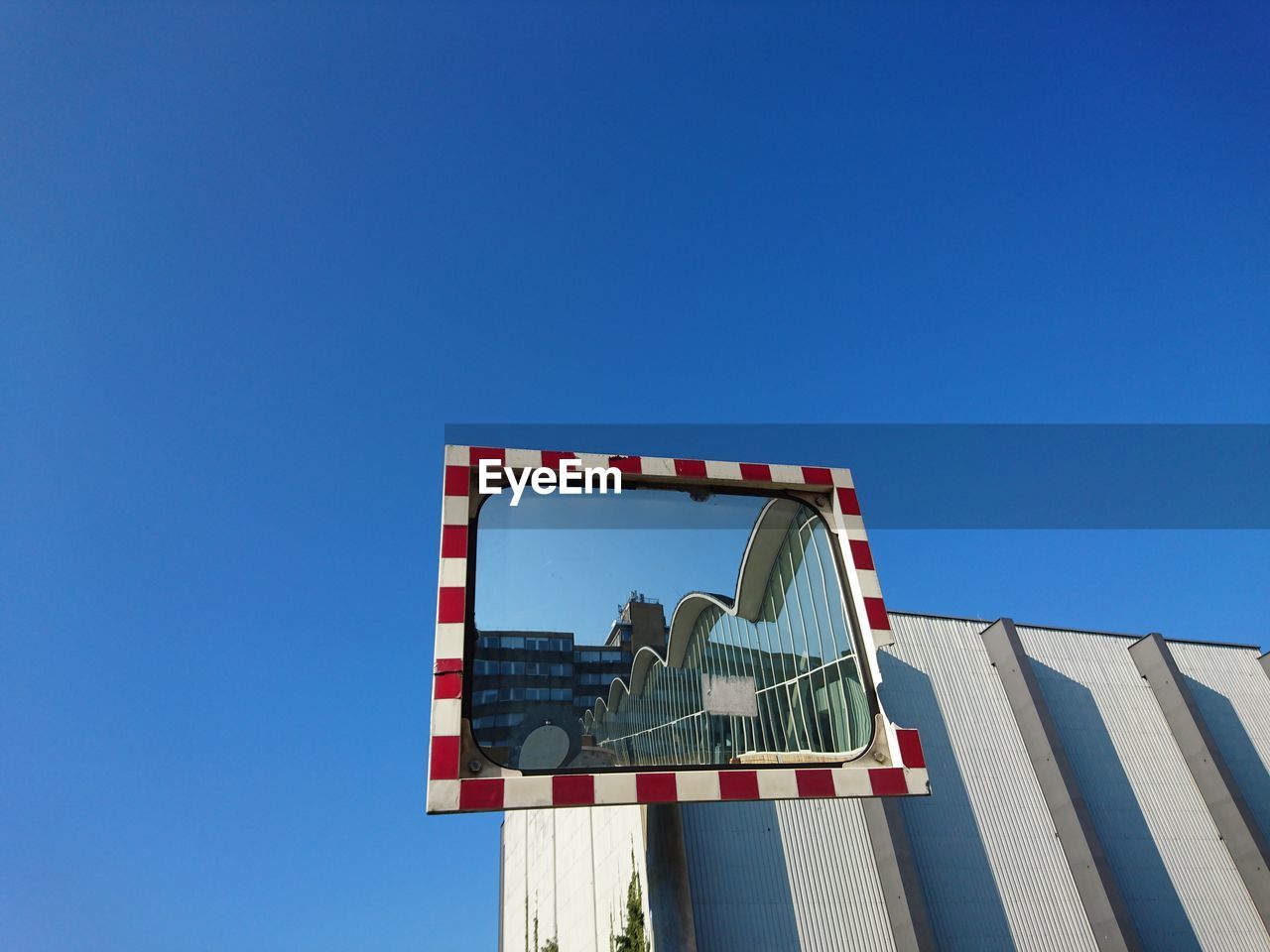 Low angle view of building reflecting in mirror against clear sky