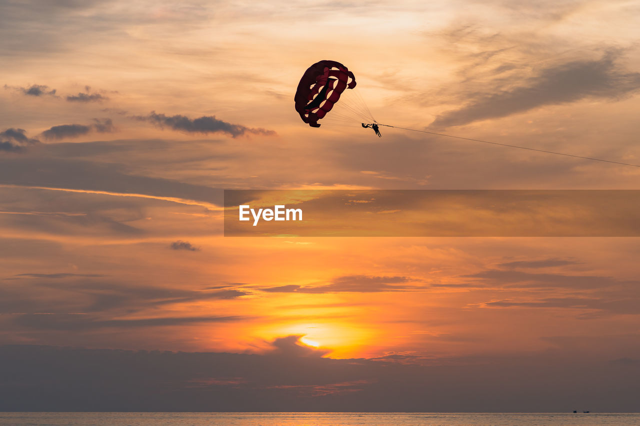 Sihouette paramotor pilot with a sunset sea scape as a background