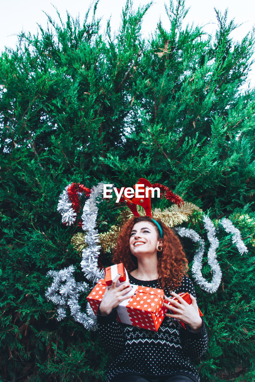 Smiling young women standing against tree