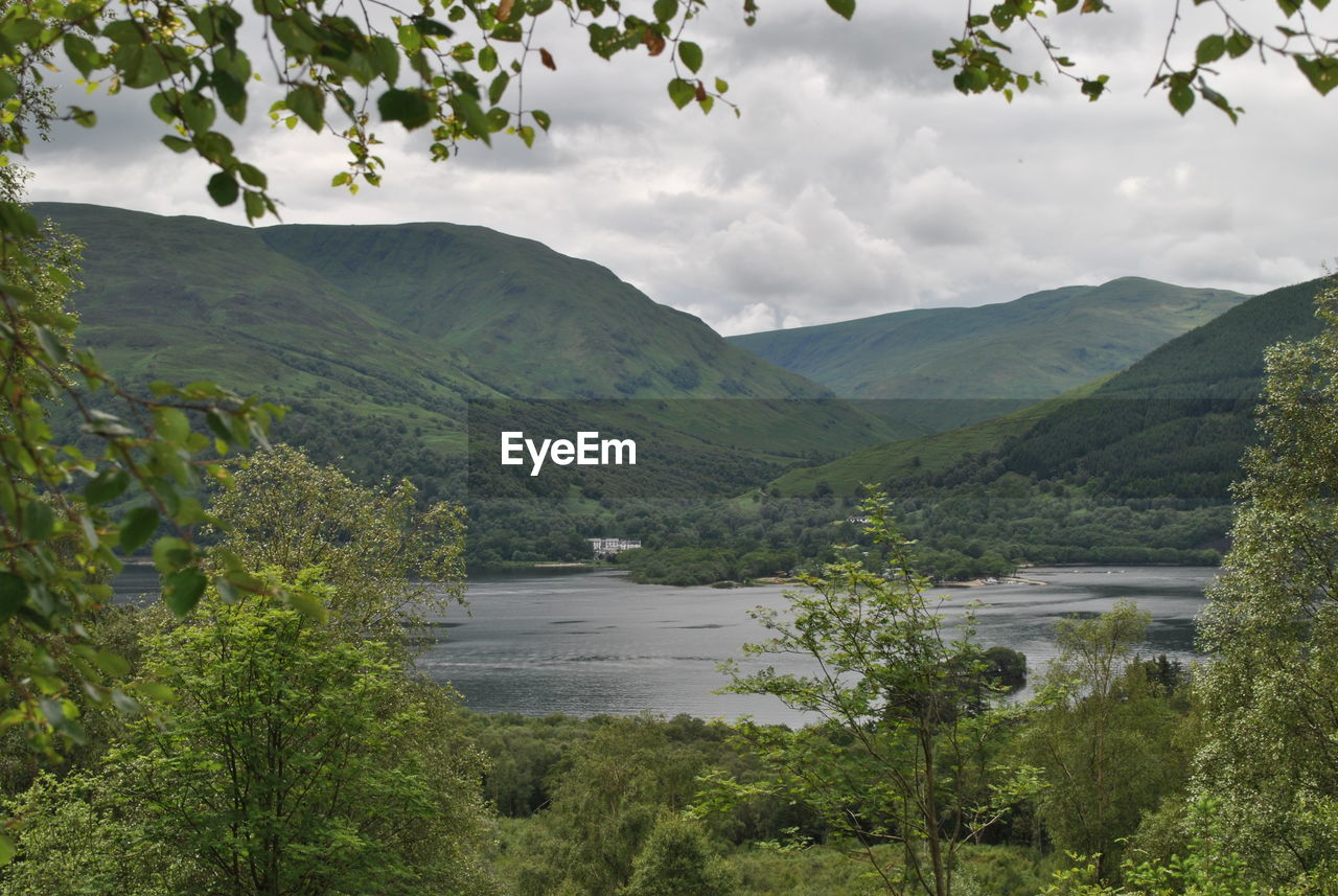 Scenic view of lake by green mountains against sky