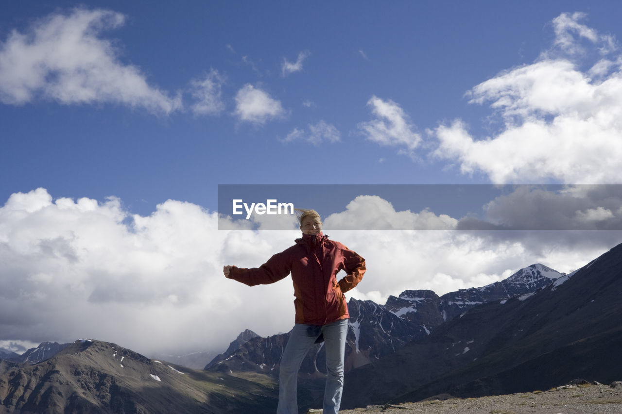 Low angle view of woman standing on whistler mountain against cloudy sky