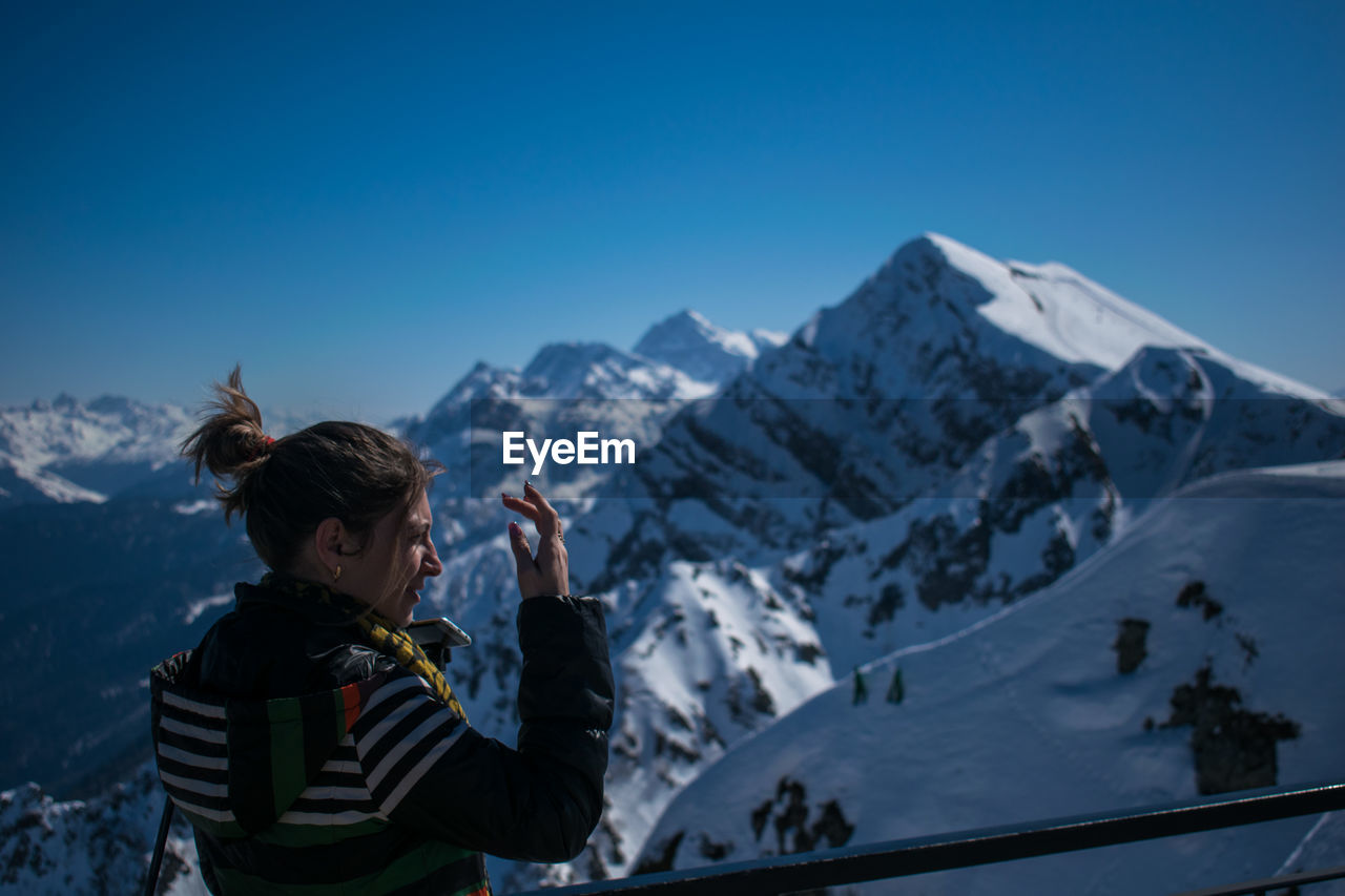 Rear view of woman standing against snowcapped mountain