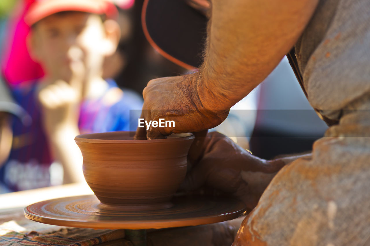 Midsection of potter making bowl in market