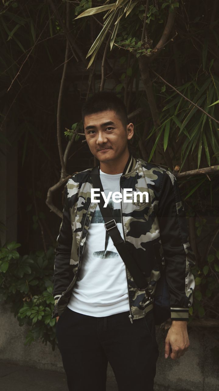 PORTRAIT OF SMILING YOUNG MAN IN FOREST