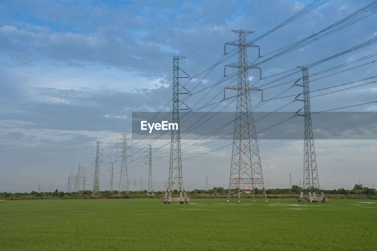 Electricity pylon on field against sky