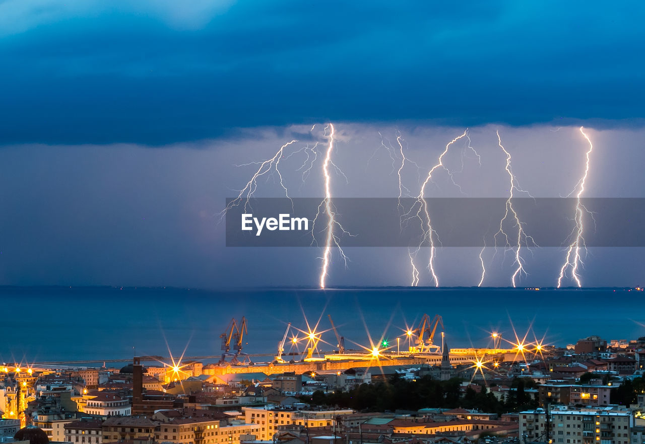 Lightning over sea against city at night