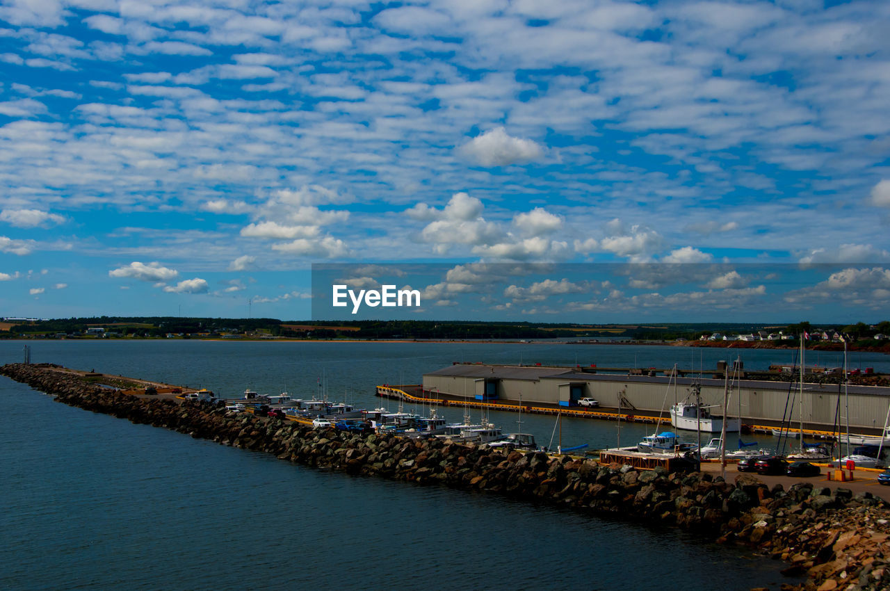 SAILBOATS MOORED ON PIER AT HARBOR AGAINST SKY