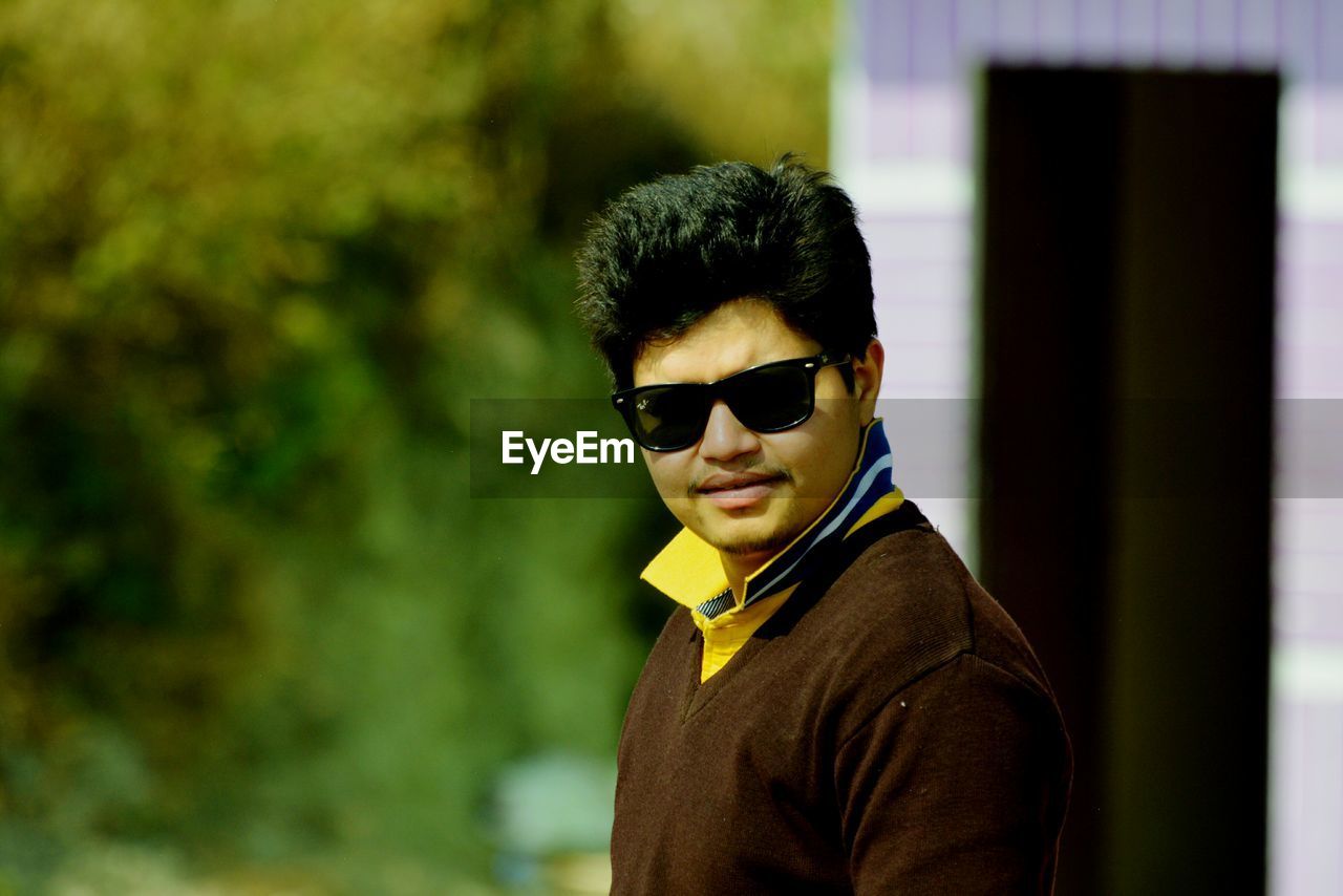 Portrait of young man wearing sunglasses while standing outdoors