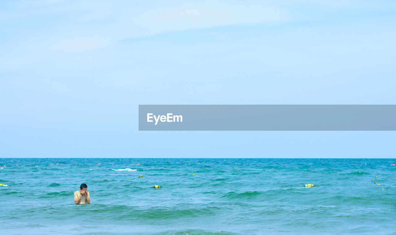 PERSON SWIMMING IN SEA AGAINST SKY