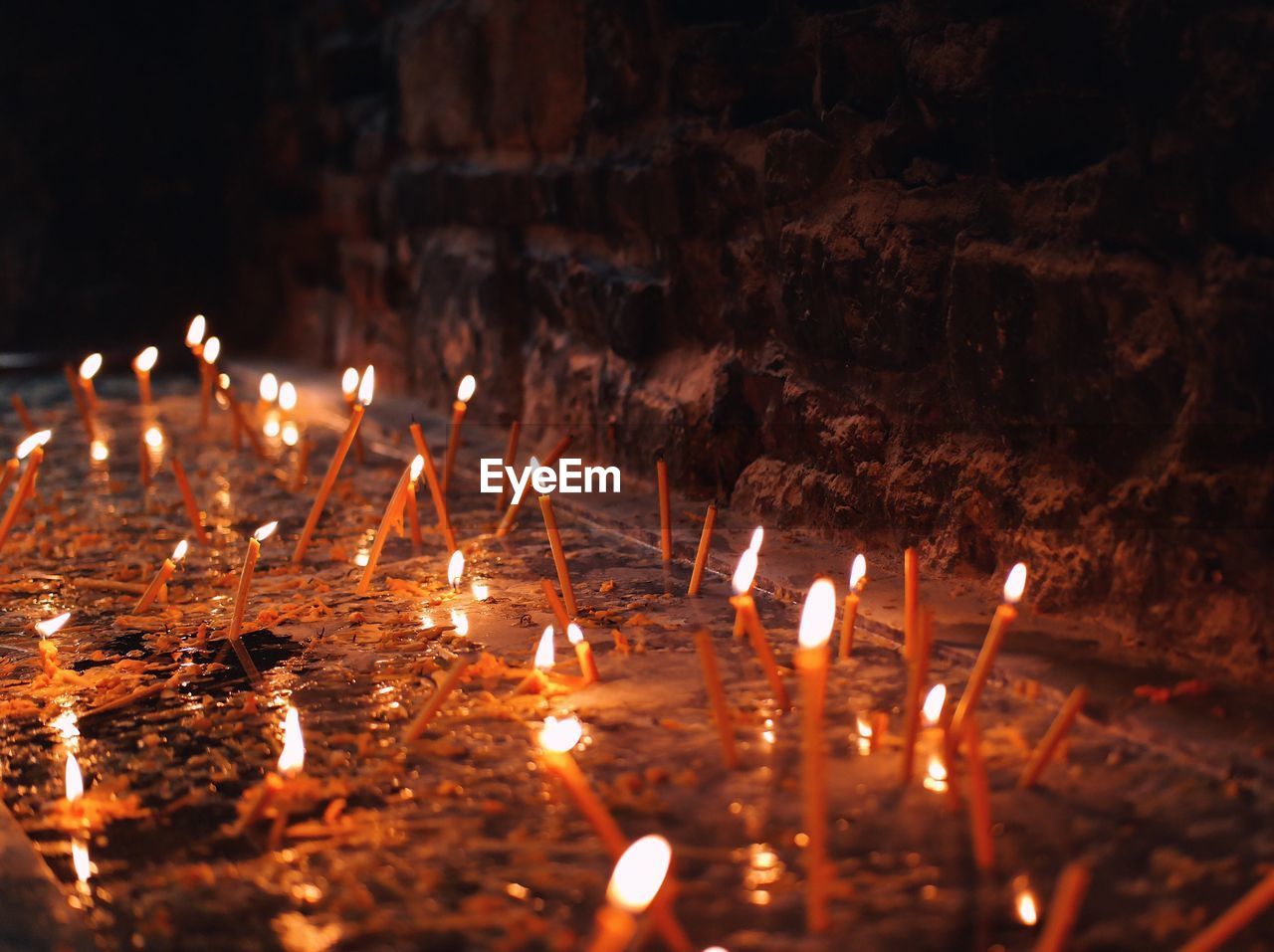 CLOSE-UP OF ILLUMINATED CANDLES IN TEMPLE