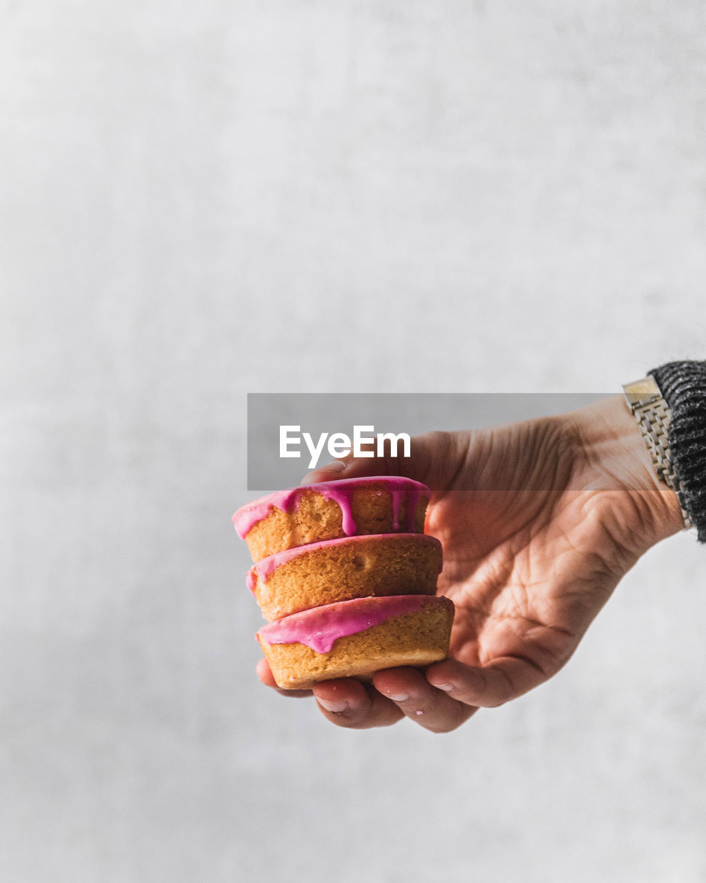 Midsection of female hand holding stack of roze koeken typical dutch pink iced cakes