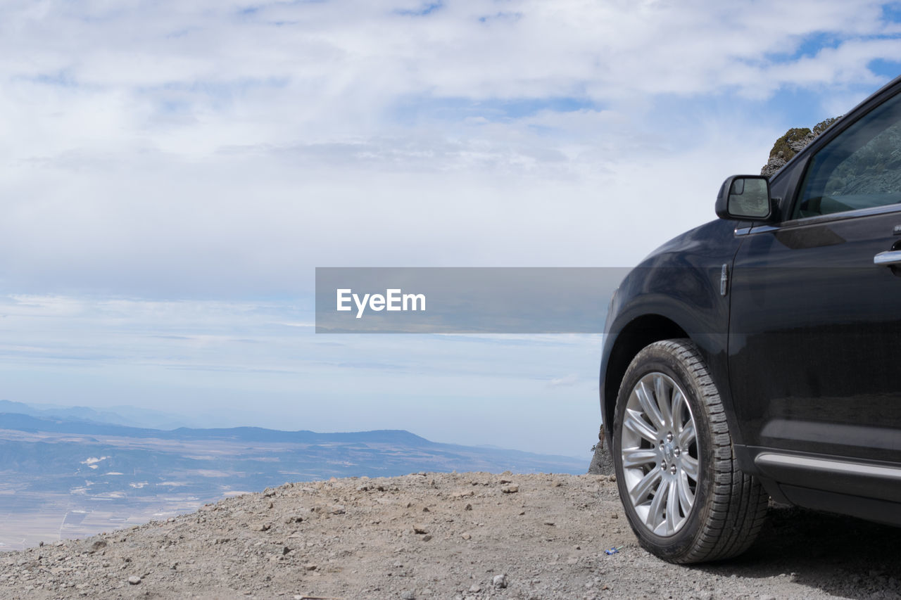 Car parked on cliff against sky