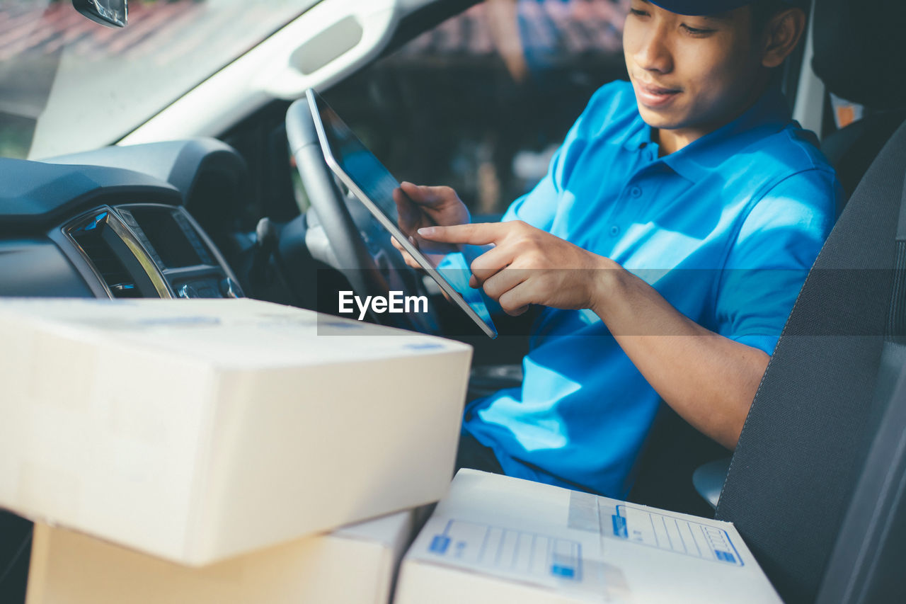 Man using digital tablet while sitting in car