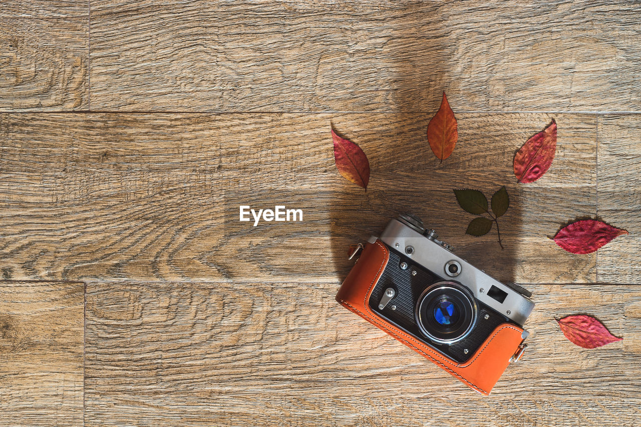 Old retro photo camera on wooden background. autumn composition with dry color leaves. flat lay