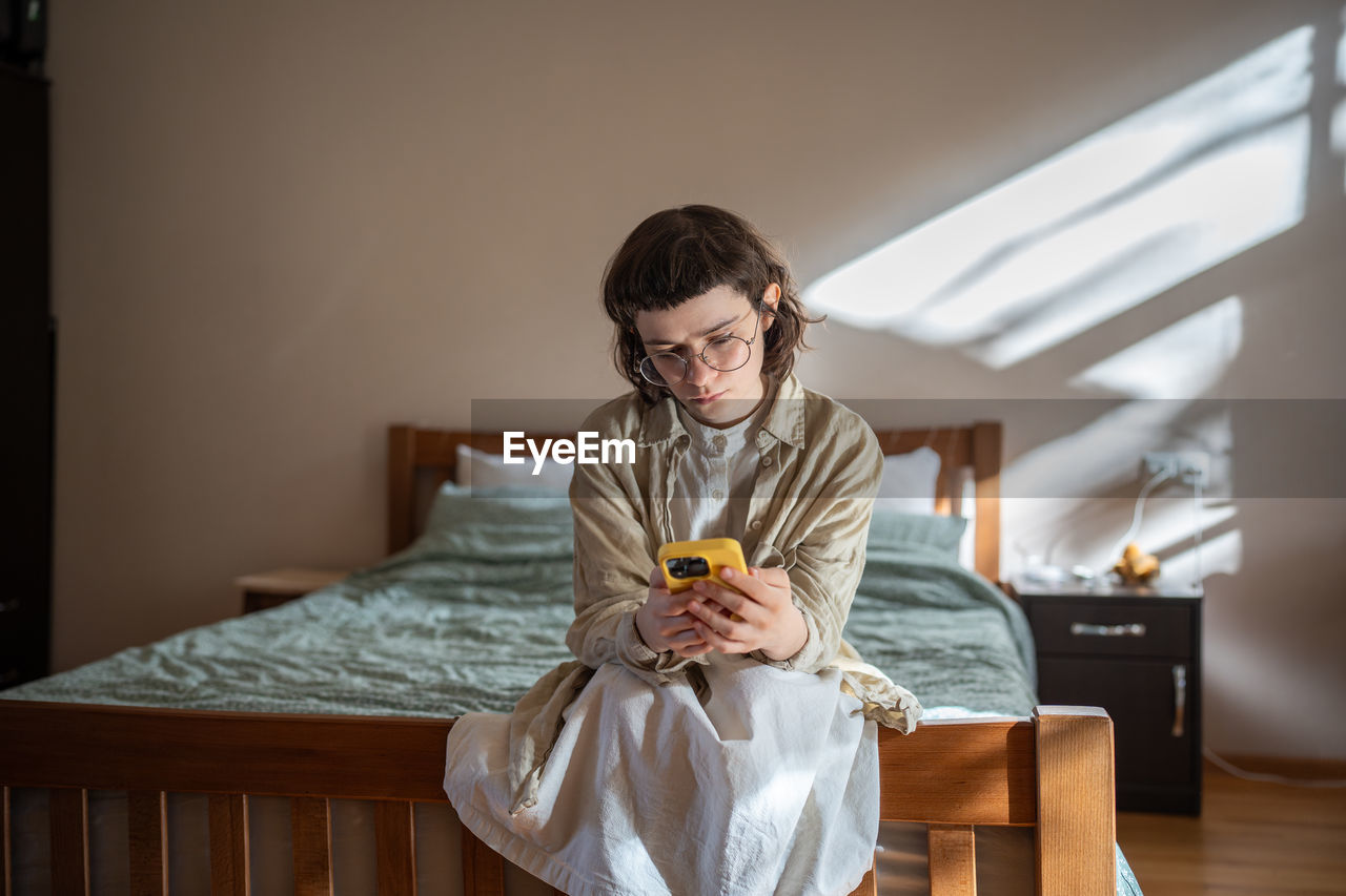 portrait of young woman sitting on bed