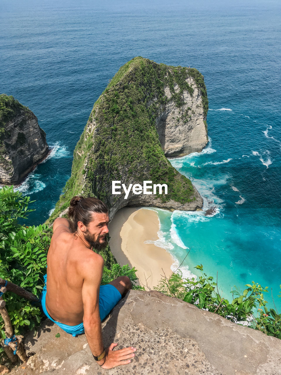 HIGH ANGLE VIEW OF MAN ON ROCK AT BEACH