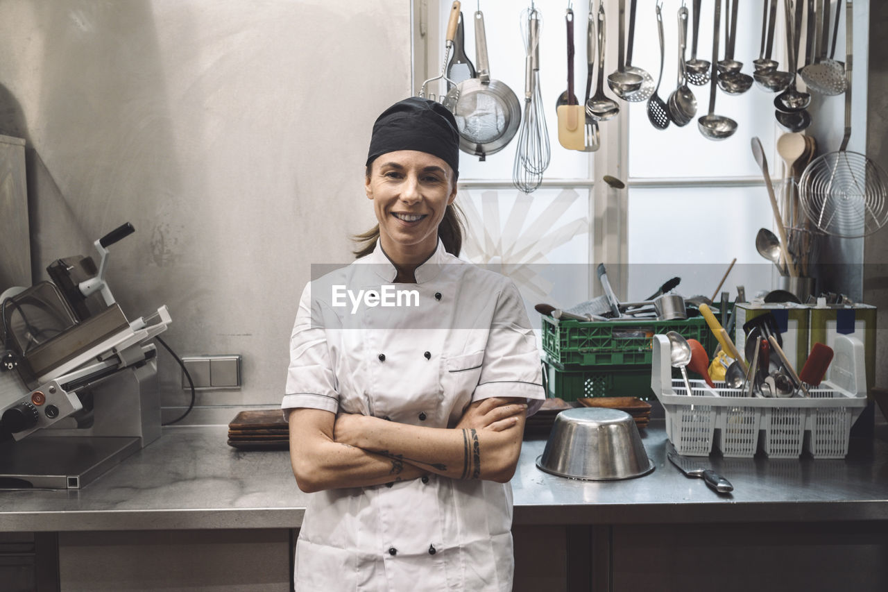 Portrait of smiling female chef with arms crossed in commercial kitchen