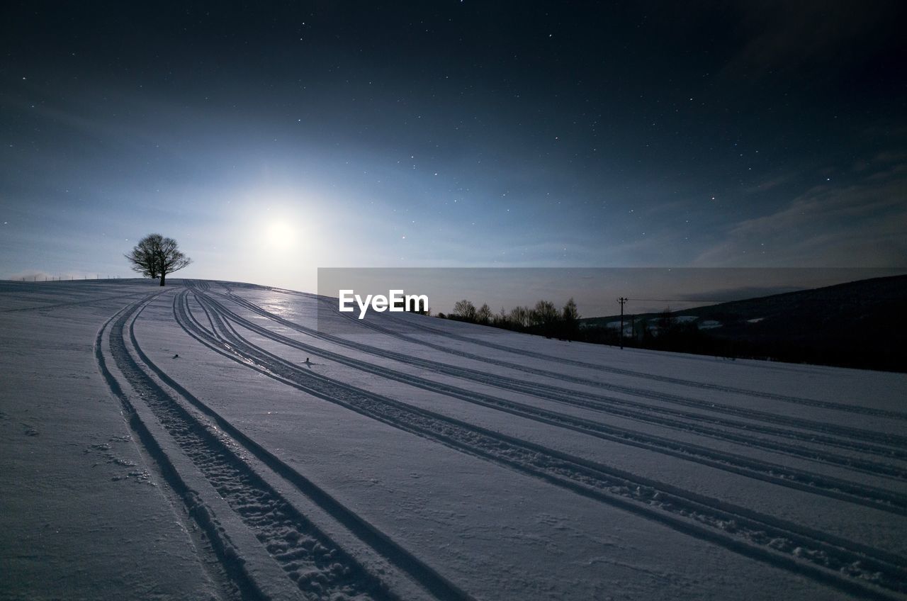 Snow covered landscape against sky at night