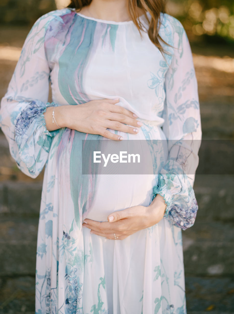 MIDSECTION OF WOMAN STANDING BY TREE